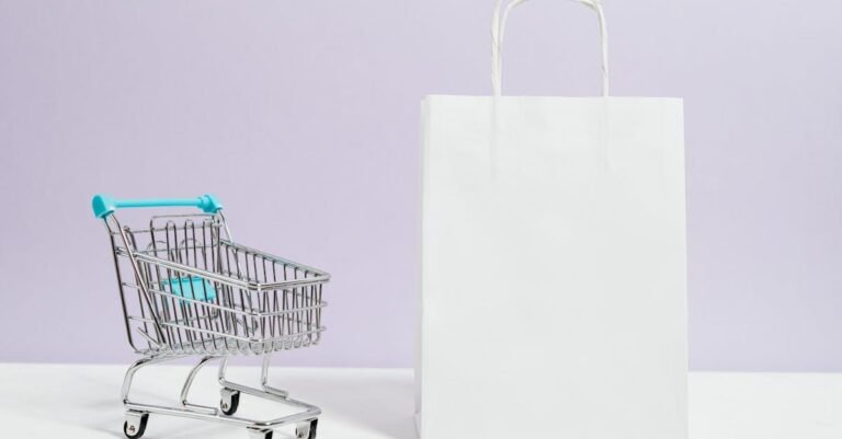 Minimalist image of a white shopping bag and mini cart on a soft pastel background.