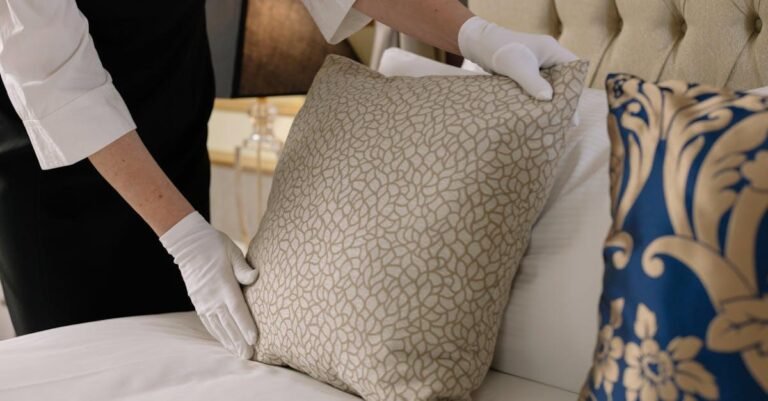 Elegant hotel bedding arrangement by a professional housekeeper in uniform.