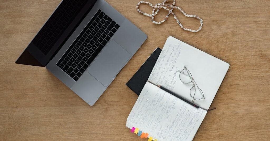 A neat desk setup with laptop, notebook, and glasses on a wooden surface, perfect for studying or working from home.