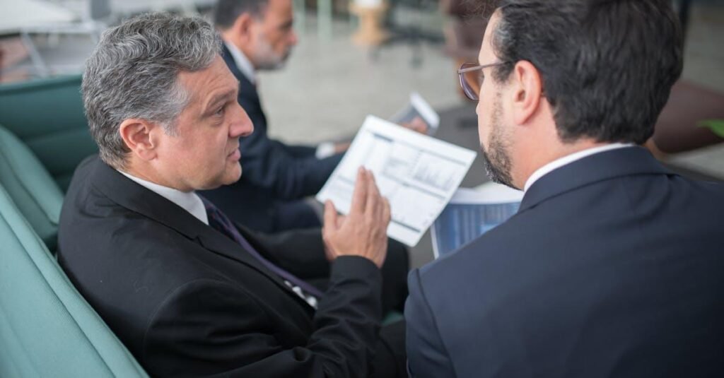 Two businessmen engaged in a discussion, examining reports in a modern office environment.